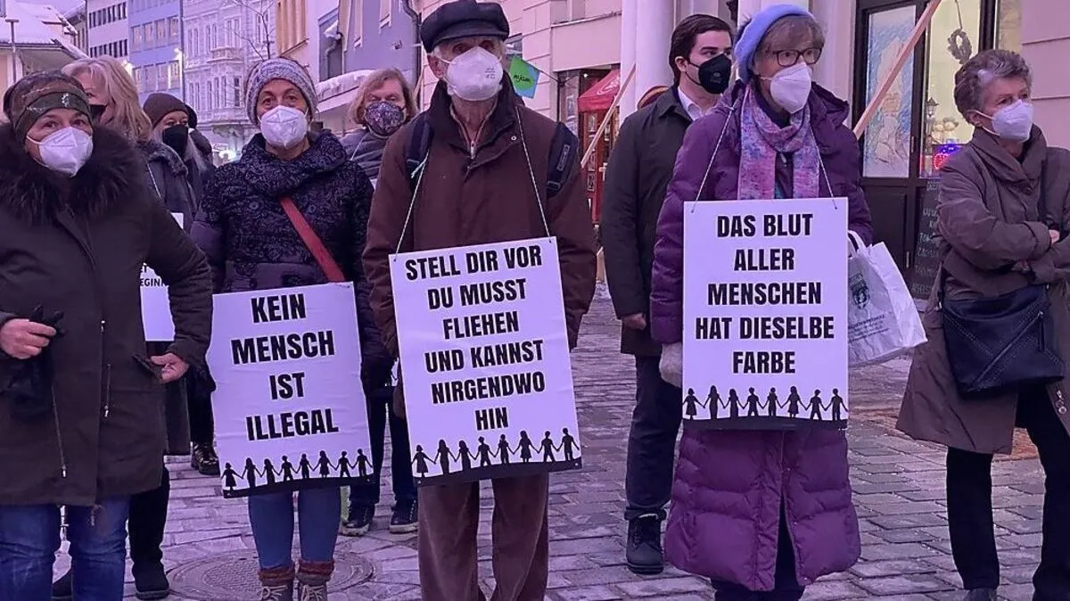 Mit umgehängten Tafel gedachten Menschen den Opfern des Nationalsozialismus bei einer Mahnwache am Hans-Gasser-Platz