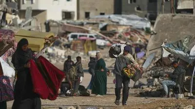 A Palestinian man carries bags of firewood after collecting them from the rubbish in Khan Younis, southern Gaza Strip, on Saturday, Nov. 15, 2025. (AP Photo/Abdel Kareem Hana)