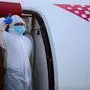 A crew member gestures from plane  door after landing at Zagreb International Airport following the evacuation of Croation nationals from Italy and Spain by their government following the spread of the  the novel coronavirus, COVID-19, which has killed many hundreds of people in both countries on April 4, 2020. (Photo by Denis LOVROVIC / AFP)