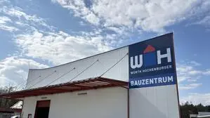 Außenansicht auf eine Lagerhalle mit einem blauen Logo rechts auf der Wand