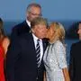 TOPSHOT - French President's wife Brigitte Macron (C-R) kisses US President Donald Trump (C-L), flanked by US First Lady Melania Trump (L) and France's President Emmanuel Macron (R), prior to a family picture with G7 leaders and guests, on the second day of the annual G7 summit in Biarritz, south-west France on August 25, 2019. (Photo by Ludovic MARIN / AFP)