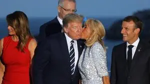 TOPSHOT - French President's wife Brigitte Macron (C-R) kisses US President Donald Trump (C-L), flanked by US First Lady Melania Trump (L) and France's President Emmanuel Macron (R), prior to a family picture with G7 leaders and guests, on the second day of the annual G7 summit in Biarritz, south-west France on August 25, 2019. (Photo by Ludovic MARIN / AFP)