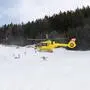 Eine Skipiste, auf der ein gelber Hubschrauber zu landen versucht. 