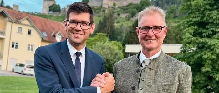 Zwei Männer klatschen ab und lächeln in die Kamera.