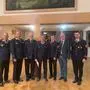 Mehrere Männer in Feuerwehruniformen stehen in einem Saal
