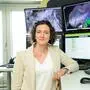 Marlies Kriegler steht vor mehreren Bildschirmen, die Grafiken zum aktuellen Wettergeschehen zeigen
