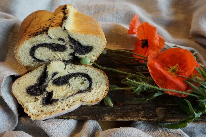 Rezept für "Mohnwoaza" Zutaten. 500 g glattes Mehl, 1 Würfel Germ, 1/4 l Milch (bei Bedarf etwas mehr), 60 g Butter, 60 g Zucker, 1 TL Salz, 2 Eier, feingeriebene Schale einer halben Biozitrone.Fülle: 50 g geriebener Mohn, 1/4 l Milch, 100 gHonig, 2 EL Rum, 2 TL Zimt, Saft einer halben Zitrone,1 Handvoll Rosinen. Zubereitung. Etwas Milch leicht erwärmen, Germ darin auflösen, Dampfl zubereiten. An warmen Platz zugedeckt 20 Minuten gehen lassen. Restliche Milch etwas anwärmen, Salz, Butter oder Schmalz und Zucker darin auflösen und zum Mehl geben, Eier und etwas geriebene Zitronenschale dazugeben. Mit Dampfl verkneten, bis sich der Teig glatt von der Schüssel löst - bemehlt 40 Minuten rasten lassen.Fülle: Milch aufkochen, Mohn dazugegeben und noch einmal aufkochen. Masse überkühlen lassen, mit Honig, Rum, Zimt, Zitronensaft und Rosinen abschmecken. Germteig dünn auswalken, mit Fülle bestreichen und einrollen. Den Teig in eine mit Butter ausgestrichene Rein oder Reindlingform geben und zugedeckt 45 Minuten gehen lassen. In das kalte Backrohr stellen und auf 180 °C einschalten. Die Backzeit beträgt ungefähr 50 Minuten. Beim Backen ein feuerfestes Schüsserl mit Wasser ins Rohr stellen, dann trocknet der Teig weniger aus. Zehn Minuten heraußen stehen lassen und aus der Form stürzen.
