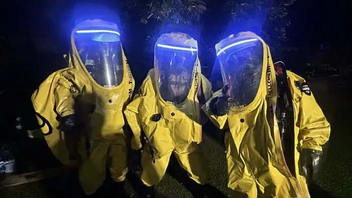 Zu sehen sind 3 Personen in einem gelben Schutzanzug