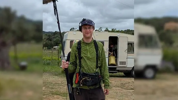 Junger Mann mit grünem Pullover hält eine Tonanlage und lächelt in die Kamera, dahinter ein Wohnmobil | Noch im vergangenen Jahr arbeitete Fabio Moser als Programmierer