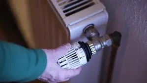 Eine Frauenhand dreht einen Heizkörper auf