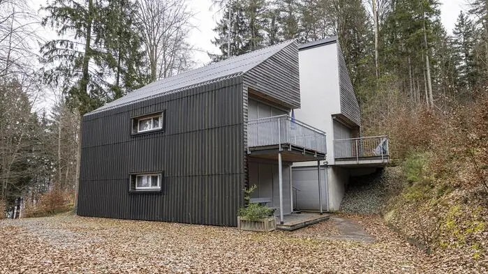 Zu sehen ist ein Haus mit einer grauen Fassade und zwei Balkonen 