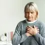 Senior adult elderly women sit on bed with chest pain suffering from heart attack in the bedroom.Healthcare and medical concept