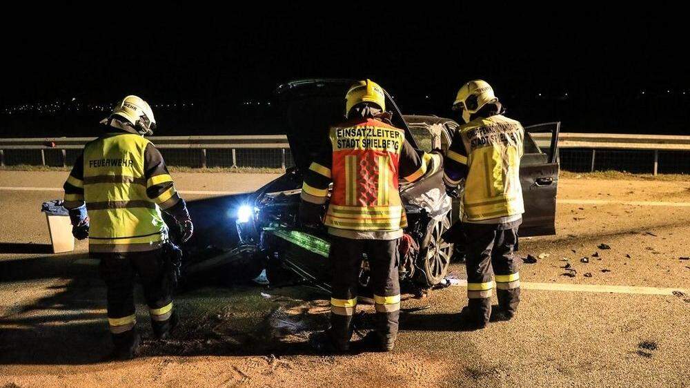 Feuerwehrleute vor dem zerbeulten Fahrzeug nach Unfall auf der S36 bei Spielberg