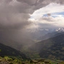 Foto mit einer Landschaftsaufnahme, die Berge, Wolken und Regen zeigt