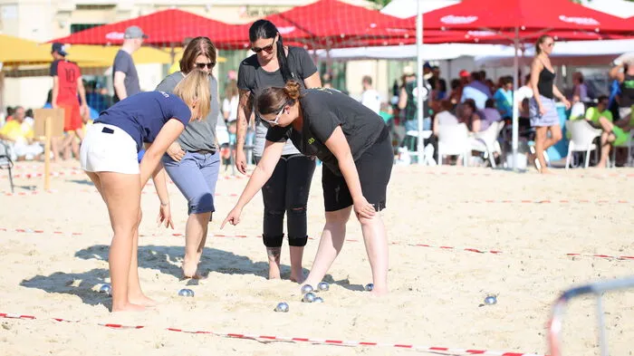 Mitten im Sand und bei sommerlichen Temperaturen haben die Spieler Spaß beim Boccia-Spielen.