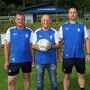Drei Herren posieren für ein Foto. Einer hält einen Fußball in den Händen.