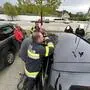 Mehrere Feuerwehrmänner versuchen eine Autotür zu öffnen