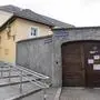 Man sieht eine Mauer und eine Stiege, in der Mauer ein großes braunes Holztor