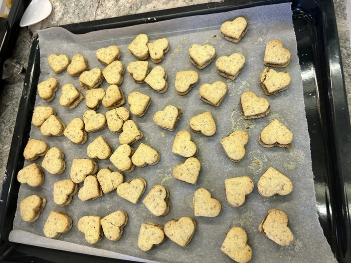 Die gebackenen Herzen vorsichtig füllen und zusammensetzen. Falls die Fülle schon ein bisschen hart geworden ist, kann man sie mit den Fingern ein wenig in Form drücken, bevor man sie auf das Keks legt.