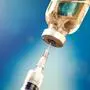 A bottle with vaccine and syringe in front of blue background. Close up shot.  Medicine, science and healthcare concept