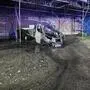 Ein verbrannter Klein-Lkw steht unter einem Gerüst nahe einer Hausmauer