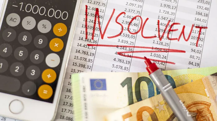 Ein Taschrenrchner, Geld und eine rote Schrift mit dem Wort Insolvenz
