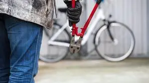 Eine Person mit Zange geht auf ein Fahrrad zu