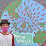 This picture taken on April 9, 2020 shows mural artist Sulis Listanto posing next to his artwork as local artists join the campaign in the fight against the COVID-19 coronavirus outbreak in Depok, West Java. - From scythe-wielding monsters to a globe fending off the COVID-19 coronavirus with an umbrella, a group of Indonesian artists has turned to wall murals to help clamp down on a surging tide of infections. (Photo by ADEK BERRY / AFP) / RESTRICTED TO EDITORIAL USE - MANDATORY MENTION OF THE ARTIST UPON PUBLICATION - TO ILLUSTRATE THE EVENT AS SPECIFIED IN THE CAPTION
