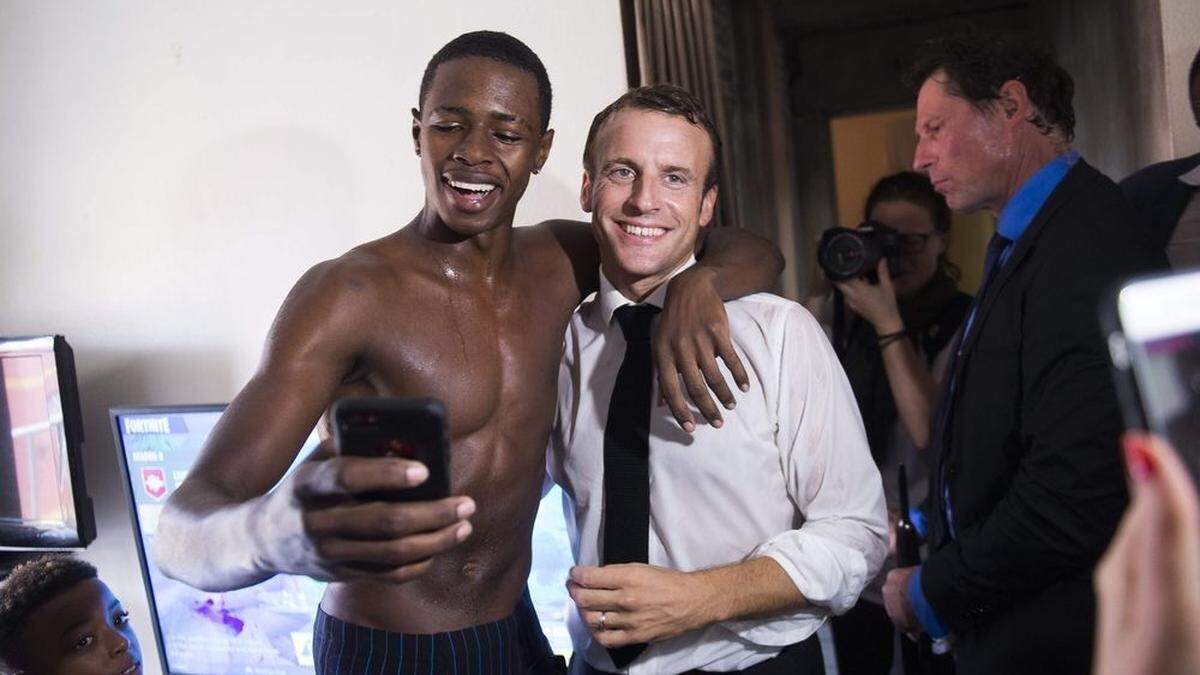 Hier lacht Macron gemeinsam mit dem jungen Mann, der auf einem weiteren Bild den Stinkefinger zeigt