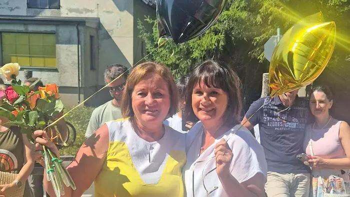 Zwei Frauen mit Luftballonen in der Hand lächeln in die Kamera