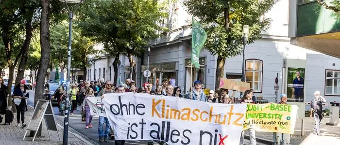 Menschen gehen mit Plakaten und Transparenten durch eine Straße