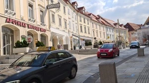 Drei Autos fahren in der historischen Altstadt von Wolfsberg