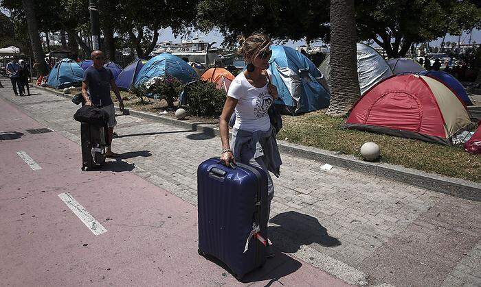 Touristen passieren Zelte der Flüchtlinge 