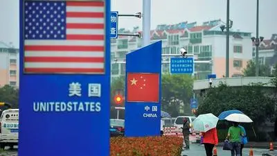 Signs with the US flag and Chinese flag are seen outside a store selling foreign goods in Qingdao in China's eastern Shandong province on September 19, 2018. - China on September 18 announced tariffs on US goods worth $60 billion in retaliation for President Donald Trump's decision to slap duties on $200 billion in Chinese products next week. (Photo by STR / AFP) / China OUT