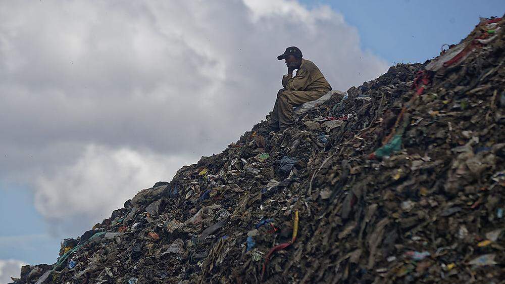 Ein Mann auf einem Berg von Müll in den Slums von Nairobi, Kenia