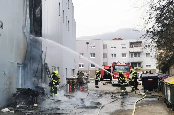 Die Flammen hatten bereits auf die Außenfassade eines Gebäudes übergegriffen. Bei einem ersten Löschangriff und der Durchsuchung des Gebäudes unter Atemschutz, wurde festgestellt, dass sich keine Personen darin befanden, ein angrenzendes Geschäft wurde evakuiert.