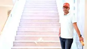 Ein Mann, Johannes Kirisits, steht an der Treppe und lehnt sich an das rechte Geländer. | Johannes „Joe“ Kirisits erzählt über sein bewegtes Leben