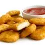 Pile of golden deep-fried battered chicken nuggets with bowl of ketchup, isolated on white.