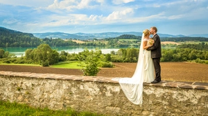 Ein Hochzeitspaar vor einer malerischen Kulisse, im Hintergrund liegt ein See, sanft in die Landschaft eingebettet.