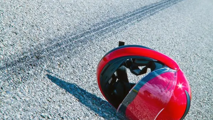 Motorradhelm liegt neben einer Bremsspur auf der Straße.