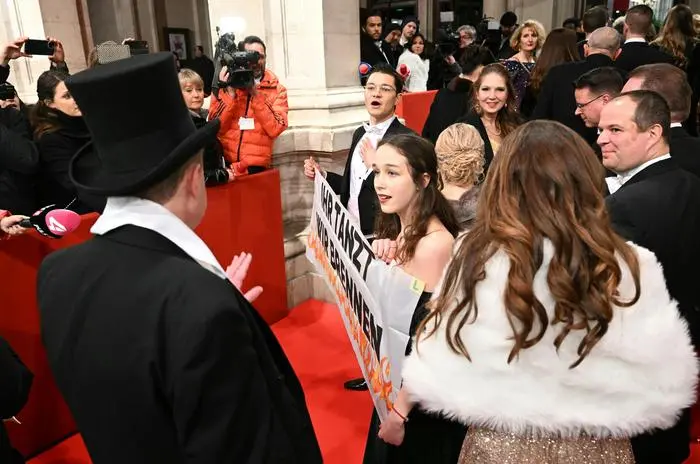 Auf dem roten Teppich vor der Staatsoper haben die Klima-Aktivisten Lena Schilling und Daniel Shams ein Banner mit der Aufschrift "Ihr tanzt, wir brennen" entrollt