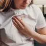 Young unhealthy female sit on couch having difficulty breathing pain of heart, touches his chest with hand. Trouble breathing, chest pain. Heart attack, thoracic osteochondrosis, panic attack concept