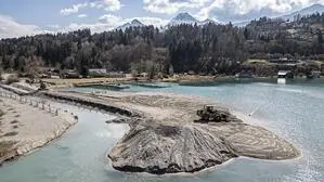 Vogelperspektive einer Sandbank in einem See. Im Hintergrund sieht man Wald