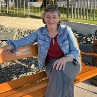 Eva-Maria Kölbl-Perner auf einer orangen Sitzbank, die Lavanttaler Soroptimistinnen als Zeichen gegen Gewalt vor dem Wolfsberger Krankenhaus aufgestellt haben