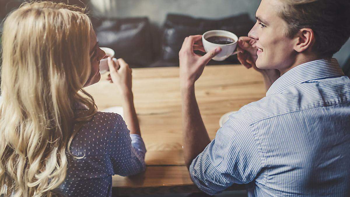 Couple of young people drinking coffee and eating cake in a stylish modern cafeteria