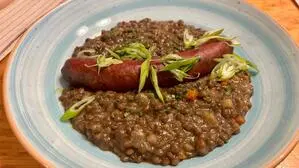 Ein Teller mit Linsen und einer Wurst in der Mitte, darüber frisches Gemüse | Am Hundsmarhof wird bodenständig gekocht