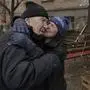 A woman kisses a man while cooking on an open fire outside an apartment building which had no electricity, water or gas since the beginning of the Russian invasion in Bucha, Ukraine, Sunday, April 3, 2022. (AP Photo/Vadim Ghirda)