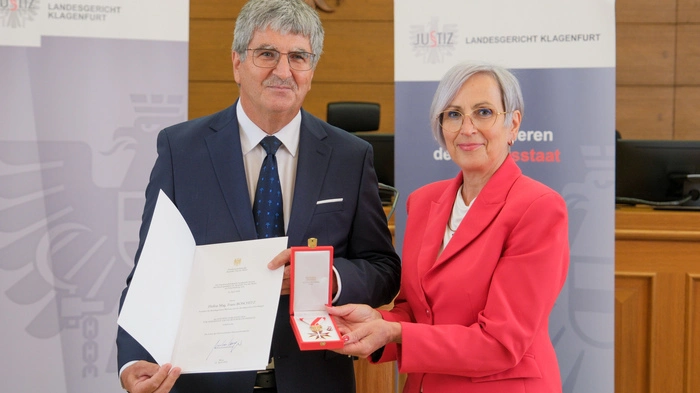 Zwei Personen halten eine Auszeichnung in der Hand 