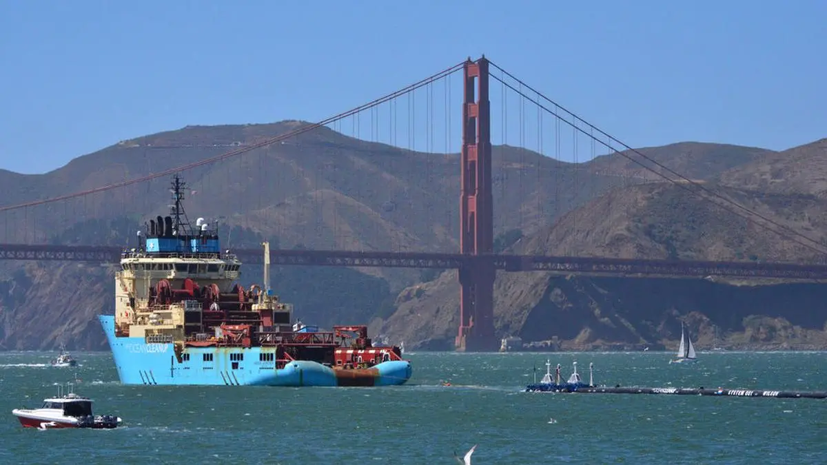File - In this Sept. 8, 2018 file photo, a ship tows The Ocean Cleanup's first buoyant trash-collecting device toward the Golden Gate Bridge in San Francisco en route to the Pacific Ocean. The trash collection device deployed to corral plastic litter floating between California and Hawaii in an attempt to clean up the world's largest garbage patch is not collecting any trash. But Boyan Slat, who launched the Pacific Ocean cleanup project, told The Associated Press in an interview Monday, Dec. 17, 2018, he is confident the 2,000-foot (600-meter) long floating boom will be fixed.  (AP Photo/Lorin Eleni Gill, File)