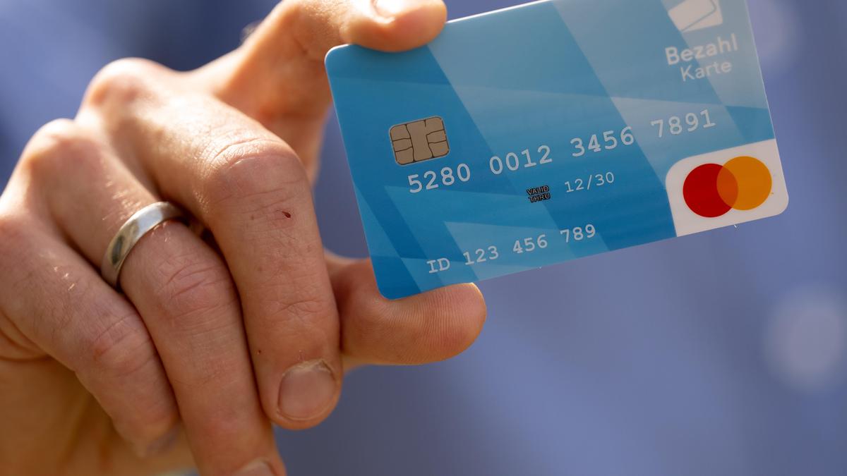 Jemand hält blaue Bezahlkarte in der Hand | Bezahlkarte bei einer Präsentation in Deutschland